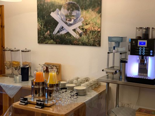 Buffet mit Getränken, darunter Saft und Kaffee, in einem einladenden Raum.