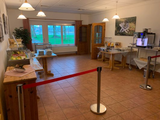 Ein Raum mit Tischen für ein Buffet, umgeben von Fenstern und warmem Licht.