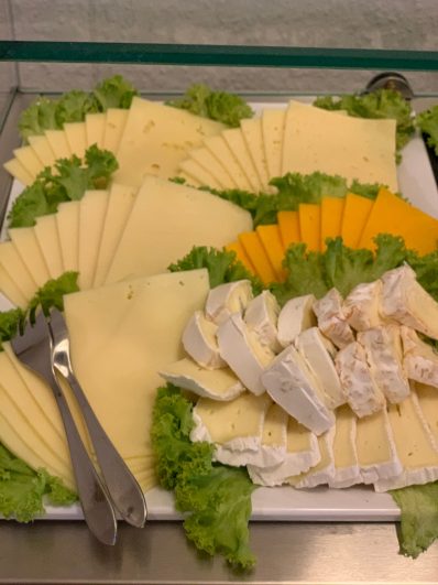 Eine Auswahl an Käsesorten, umgeben von Blattsalat.